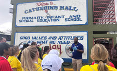 Volunteering travel advisors listen to instructions outside of Catherine Hall Primary School, where they paint and organize donations.