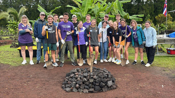 A group of students on the Imu Mea Ai tour complete building an imu, a traditional Hawaiian underground oven.